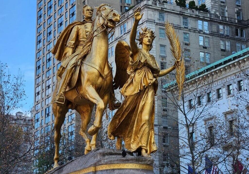 A statue of two people on horseback in front of a building.